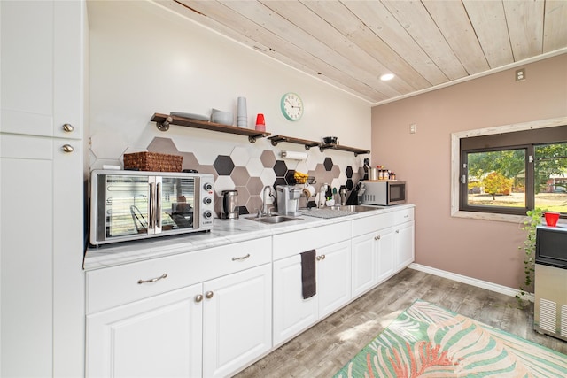 bar with sink, wood ceiling, white cabinetry, light hardwood / wood-style floors, and backsplash