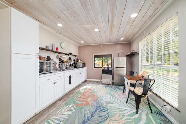 kitchen with white cabinetry, stainless steel appliances, light hardwood / wood-style floors, and wood ceiling