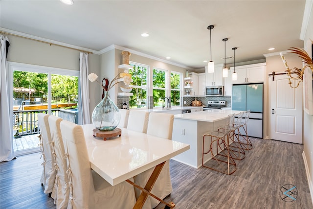 kitchen with dark wood-type flooring, stainless steel appliances, a center island, ornamental molding, and white cabinets