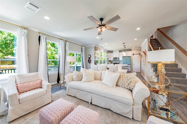 living room with crown molding, ceiling fan, and light wood-type flooring