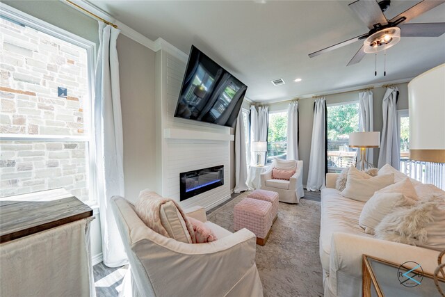 living room with ornamental molding, a large fireplace, and ceiling fan