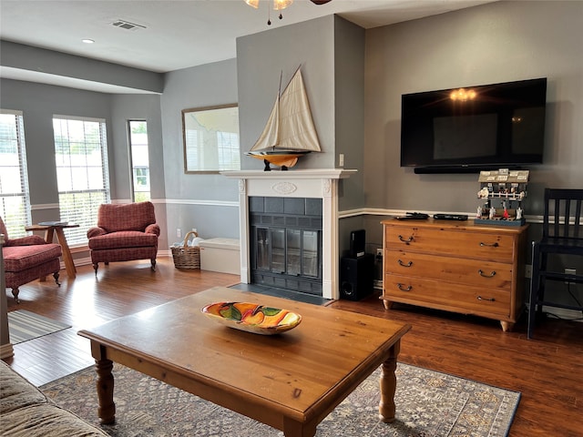 living room featuring ceiling fan, a tile fireplace, and dark hardwood / wood-style flooring