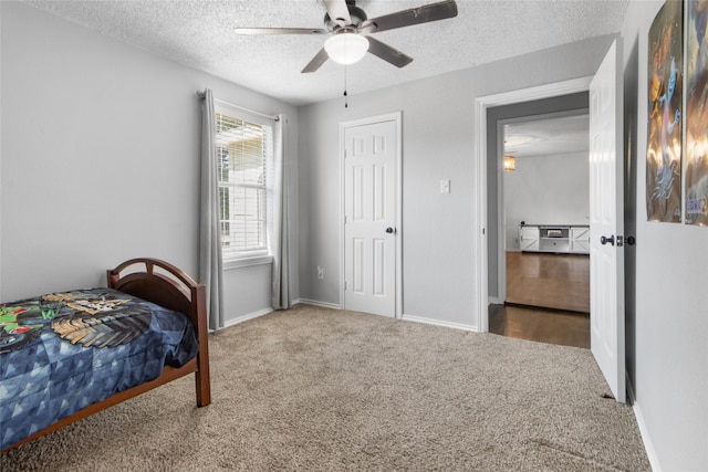 carpeted bedroom featuring ceiling fan and a textured ceiling