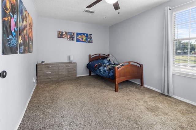 bedroom with ceiling fan, light colored carpet, and a textured ceiling