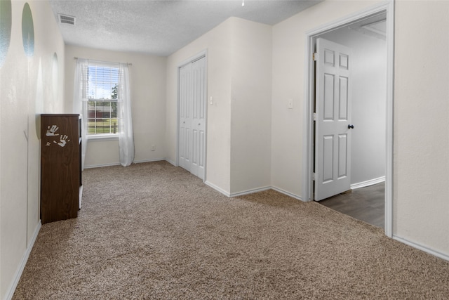 unfurnished bedroom with a textured ceiling and carpet flooring