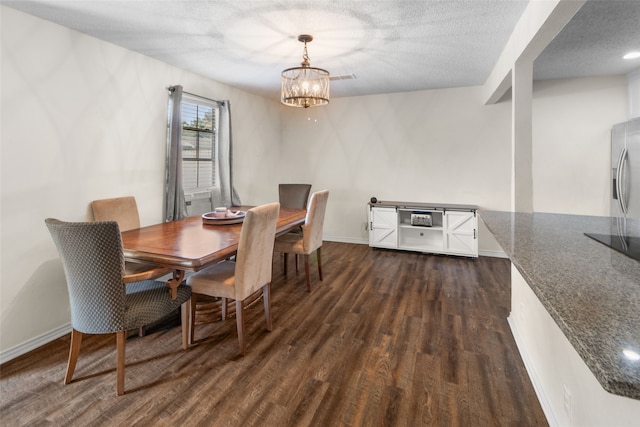 dining space with dark wood-type flooring, an inviting chandelier, and a textured ceiling