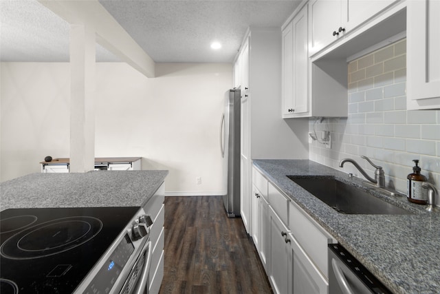 kitchen featuring appliances with stainless steel finishes, white cabinetry, dark wood-type flooring, tasteful backsplash, and a textured ceiling