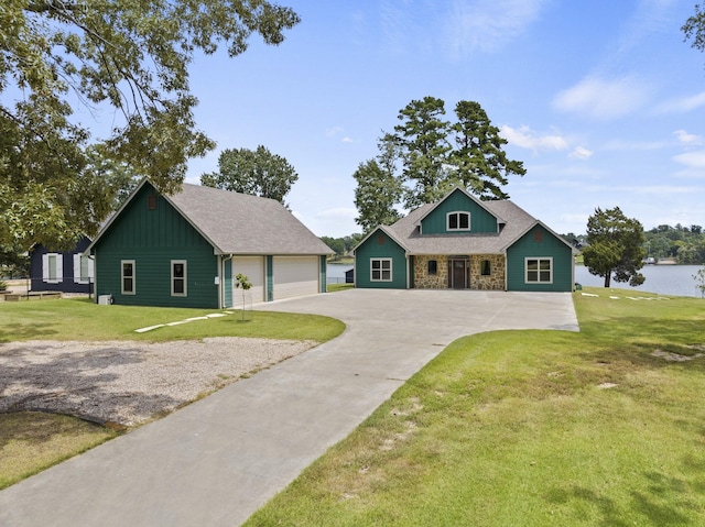 view of front of house with stone siding, a detached garage, roof with shingles, a front lawn, and board and batten siding