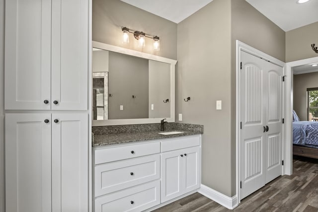 ensuite bathroom with connected bathroom, vanity, baseboards, and wood finished floors