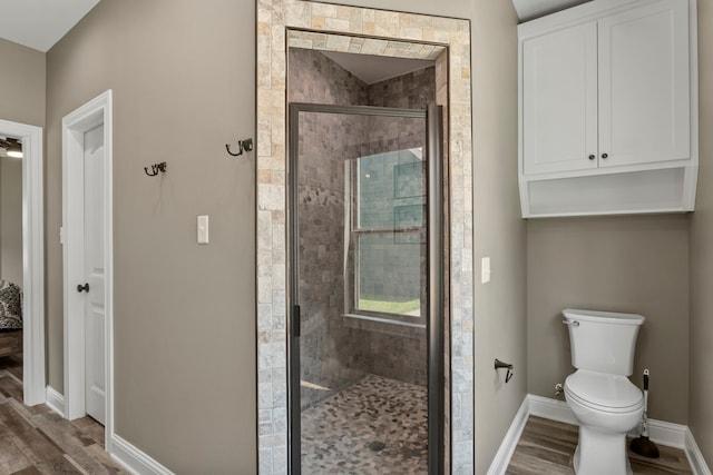 bathroom with wood-type flooring, walk in shower, and toilet