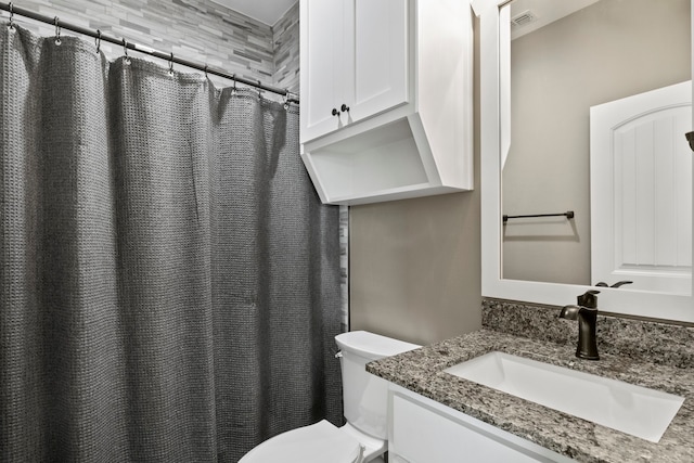 bathroom featuring toilet, vanity, and a shower with curtain