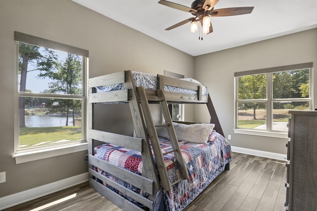 bedroom featuring a water view, baseboards, and wood finished floors