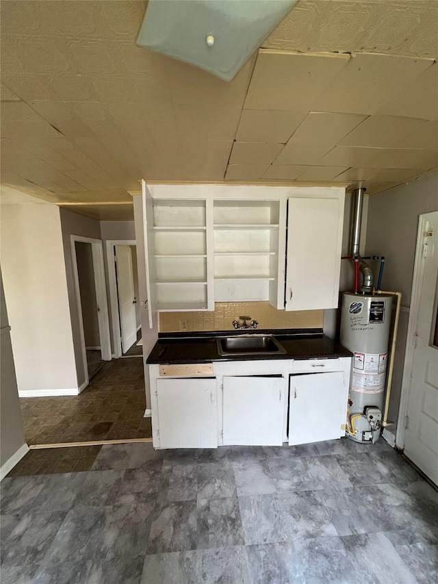 kitchen featuring sink, water heater, and dark tile patterned floors