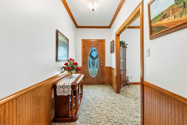 entryway featuring a wainscoted wall, carpet floors, ornamental molding, and wooden walls