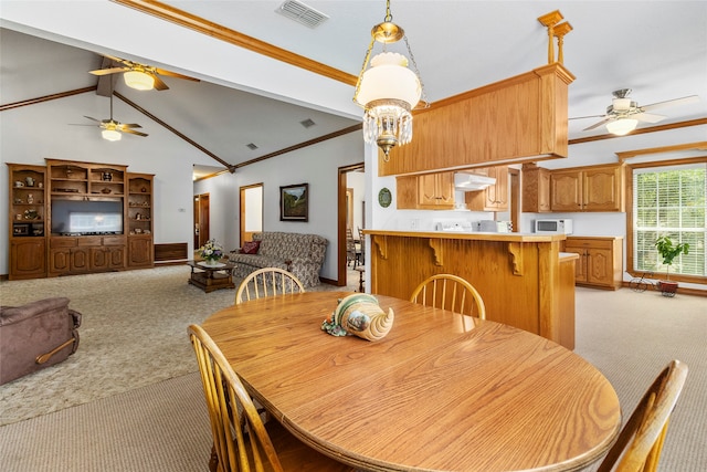 carpeted dining room featuring ceiling fan, vaulted ceiling with beams, and ornamental molding