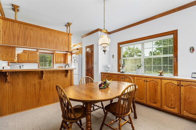 dining space featuring a wealth of natural light, ornamental molding, and light colored carpet