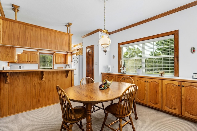 dining room with ornamental molding and light colored carpet