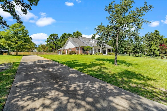 view of front of house with concrete driveway, a front lawn, and fence