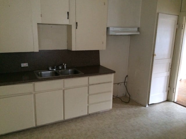 kitchen with backsplash, range hood, white cabinets, sink, and light tile patterned flooring