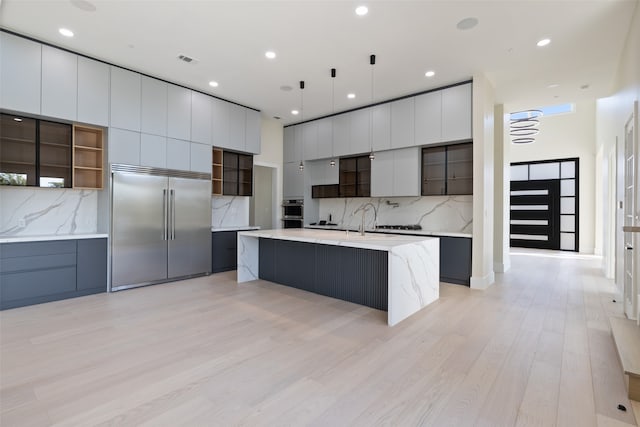 kitchen with stainless steel appliances, tasteful backsplash, light hardwood / wood-style floors, hanging light fixtures, and a large island