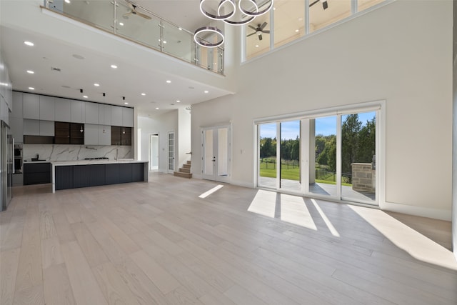 unfurnished living room featuring light wood-type flooring and a towering ceiling