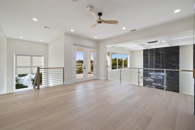 unfurnished living room with beamed ceiling, ceiling fan, french doors, and light hardwood / wood-style floors