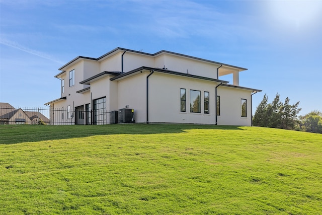 rear view of house featuring cooling unit and a yard