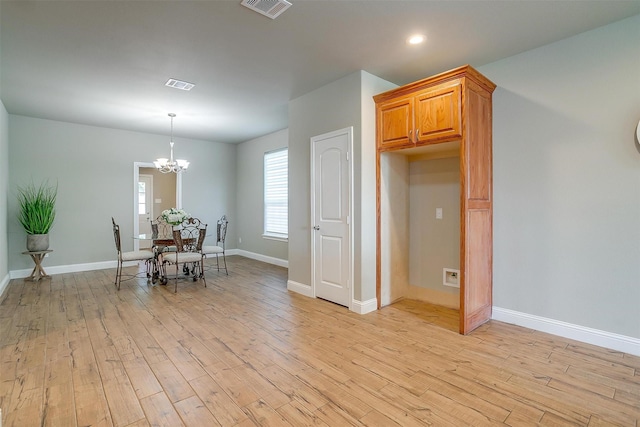 unfurnished dining area featuring an inviting chandelier and light wood-type flooring