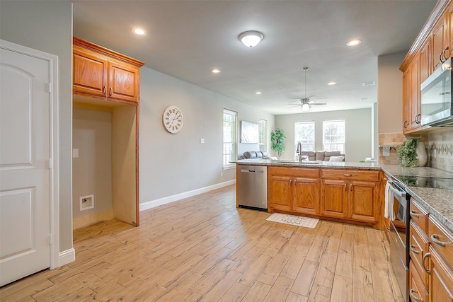 kitchen featuring sink, tasteful backsplash, kitchen peninsula, appliances with stainless steel finishes, and light wood-type flooring