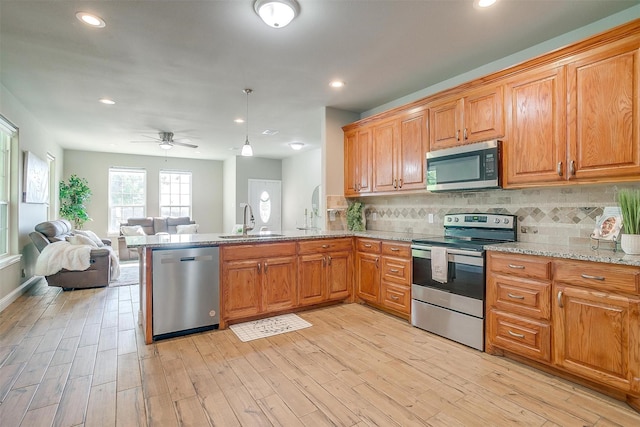 kitchen with sink, backsplash, stainless steel appliances, and light wood-type flooring