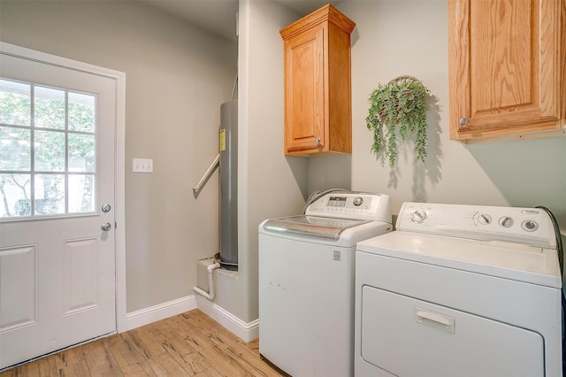 clothes washing area featuring cabinets, water heater, light hardwood / wood-style floors, and washer and dryer