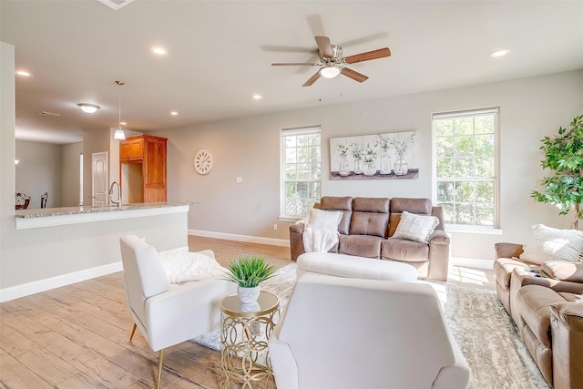 living room with ceiling fan, sink, and light wood-type flooring