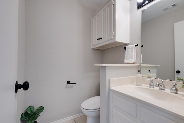 bathroom with toilet, vanity, and tile patterned floors