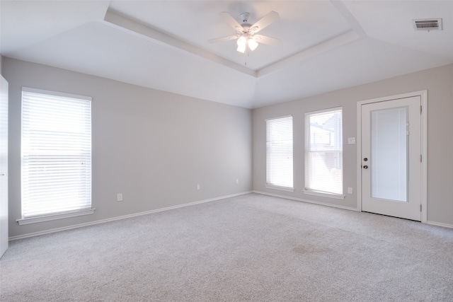 carpeted spare room with a tray ceiling and ceiling fan