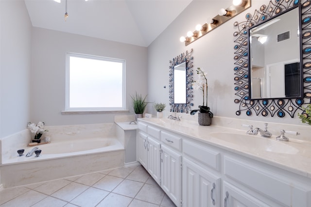 bathroom with tile patterned flooring, a bathing tub, vanity, and lofted ceiling