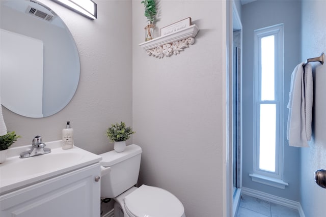 bathroom with a wealth of natural light, toilet, vanity, and tile patterned floors