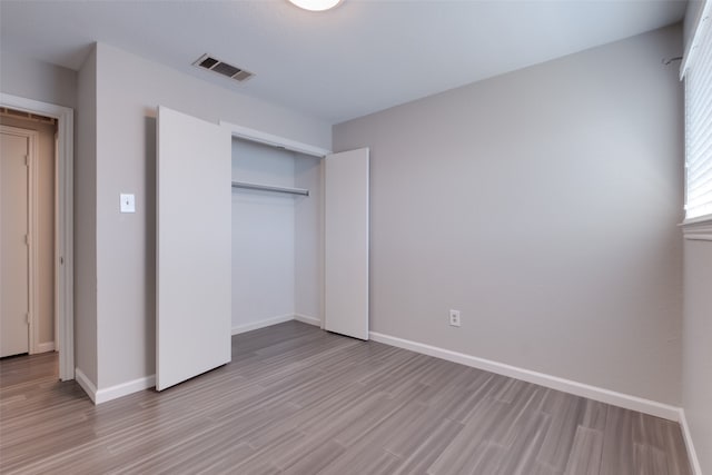 unfurnished bedroom with a closet and light hardwood / wood-style floors