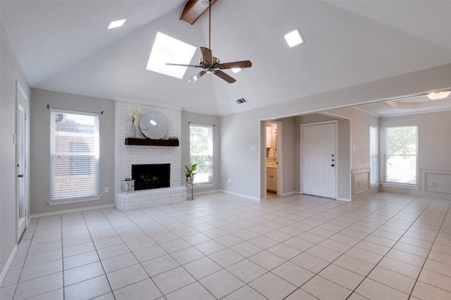 unfurnished living room with a fireplace, light tile patterned floors, vaulted ceiling with skylight, and brick wall