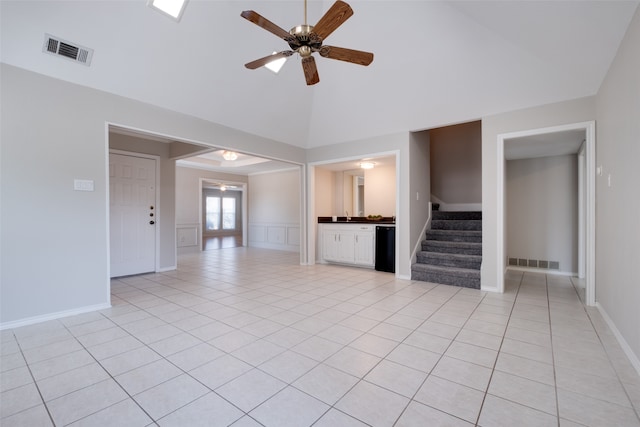 unfurnished living room with ceiling fan, light tile patterned floors, and a high ceiling