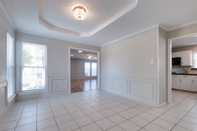 unfurnished room featuring a raised ceiling, light hardwood / wood-style floors, and ornamental molding