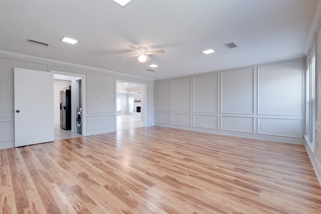 unfurnished room with ceiling fan, light wood-type flooring, washer / clothes dryer, and ornamental molding