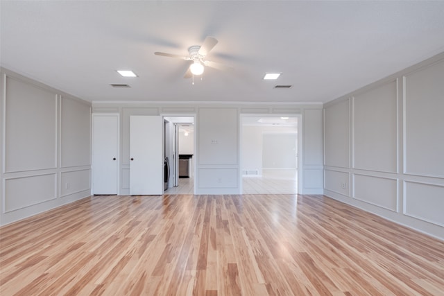 spare room with ceiling fan, stacked washer / drying machine, and light hardwood / wood-style floors