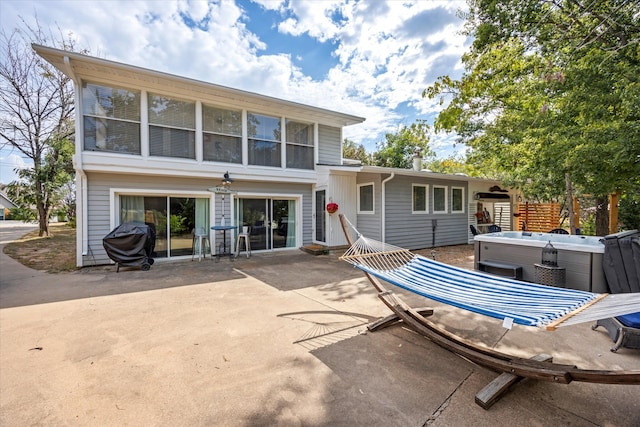 back of house with a hot tub and a patio area