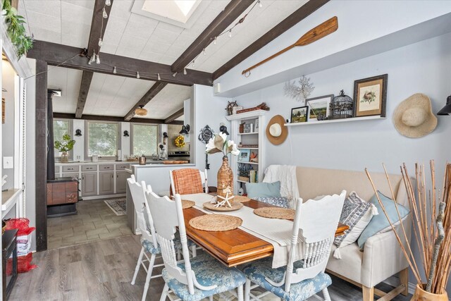 dining area featuring tile patterned flooring, a skylight, and beamed ceiling