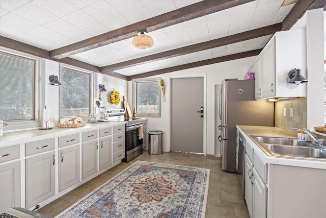 kitchen featuring tasteful backsplash, light countertops, lofted ceiling with beams, a sink, and stainless steel range with electric stovetop