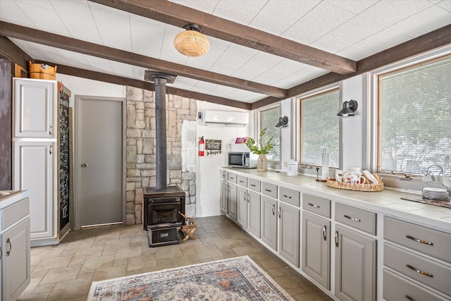 bathroom with vaulted ceiling with beams, an AC wall unit, a wood stove, tile patterned flooring, and vanity