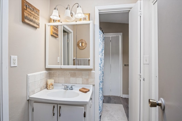 bathroom featuring wood-type flooring, decorative backsplash, and vanity