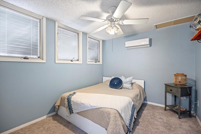 bedroom featuring ceiling fan, light colored carpet, a textured ceiling, and a wall unit AC