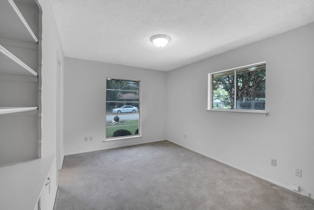 carpeted empty room with a textured ceiling