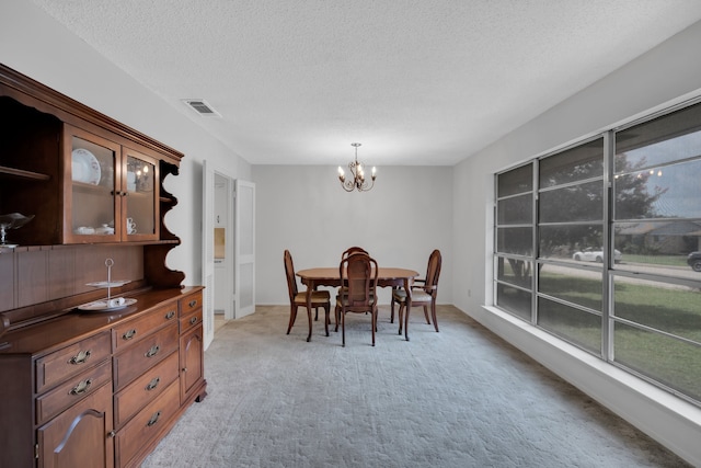 carpeted dining room with a wealth of natural light, a textured ceiling, and a chandelier